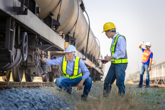 Engineers team inspecting freight tank cars at railway depot, Industrial worker and engineer conducting train safety inspection, Railway transport inspection with experts at freight train terminal