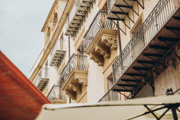 Old building facade with wrought iron balconies and carved stone corbels seen from below in the old town of Palermo Sicily Italy © Екатерина Лукашина