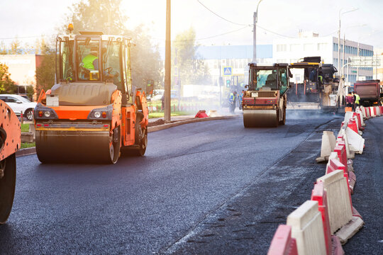 Urban Road Resurfacing Project With Heavy Machinery and Crew Compacting Fresh Asphalt