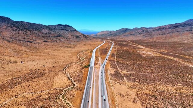 Footage over the motorways with moving cars through the barren desert. Interstate roads along the bare rocks.