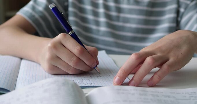 Close-up hands writing goals and plans in notebook at desk. Scene represents personal growth, planning and goal setting in calm indoor workspace environment.