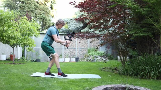 Young videographer practices professional operator walking technique with a gimbal stabilizer on grass improving smooth camera movement balance and control