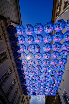Blue umbrellas above the street between buildings
