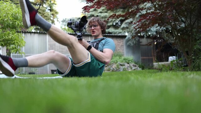 Videographer performs bicycle crunch exercise while holding a camera stabilizer developing core strength balance and stamina for demanding handheld shooting work