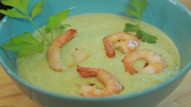 Presenting broccoli cream soup with shrimp and fresh herbs