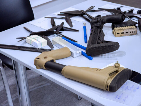 Tactical Rifle Buttstocks and Drone Propellers on Workshop Table for UAV Assembly
