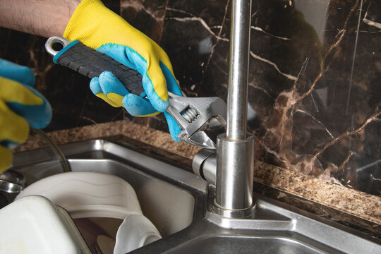 Man repairs a kitchen faucet.