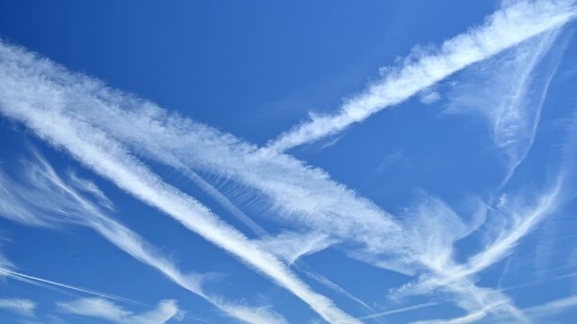 Vast blue sky filled with wispy contrails from airplanes in flight
