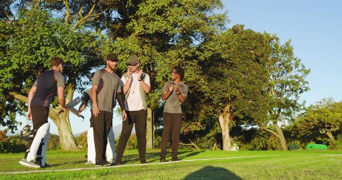 Diverse male teammates welcoming incoming teenage player with bat and helmet on outfield
