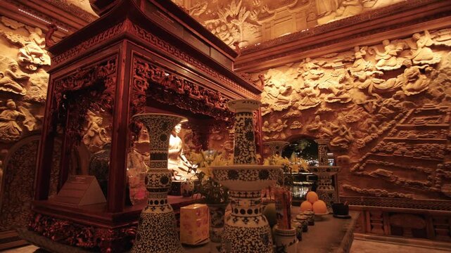 Ornate buddhist altar with offerings and wood carvings inside a traditional temple in Hoa Lu, Vietnam