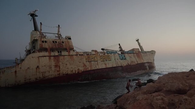Rusty old shipwreck near the coastline on sunset