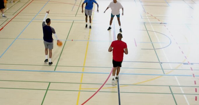 Rebounding shot, diverse male team sprinting orange basketball on court scoring layup under hoop
