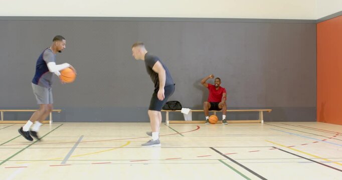 African american player dribbling basketball as defender stepping, faking pass to create space