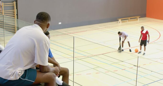 African american male teammates finishing game climbing bleachers dribbling ball greeting teammates
