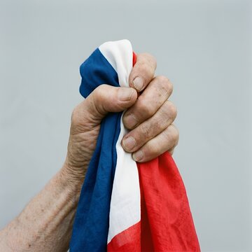 Main serrant fermement le drapeau tricolore avec fiert&eacute; et ferveur