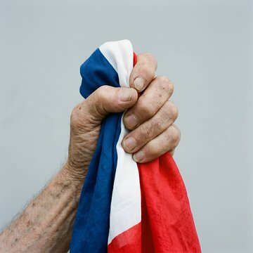 Main serrant fermement le drapeau tricolore avec fiert&eacute; et ferveur