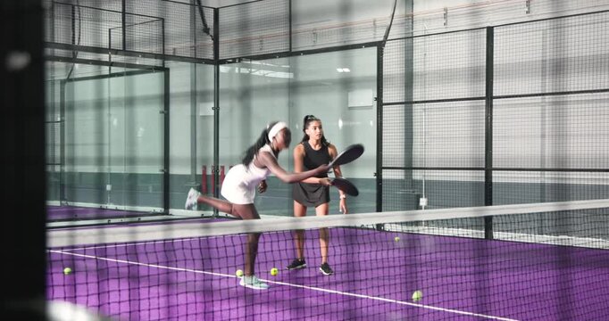 Indian coach encouraging african american student gathering balls, swinging paddle and coaching