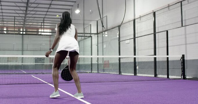 African american woman reacting to ball, grazing net cord, lunging and volleying on purple court