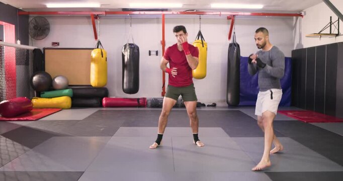 Diverse male sparring partners boxing, slipping, kicking in gym focusing form balance