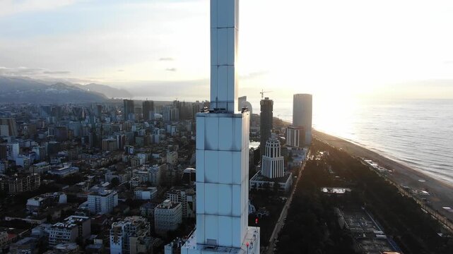 Technological university tower rising near black sea coastline, batumi georgia, construction progressing during golden sunset lighting architectural development