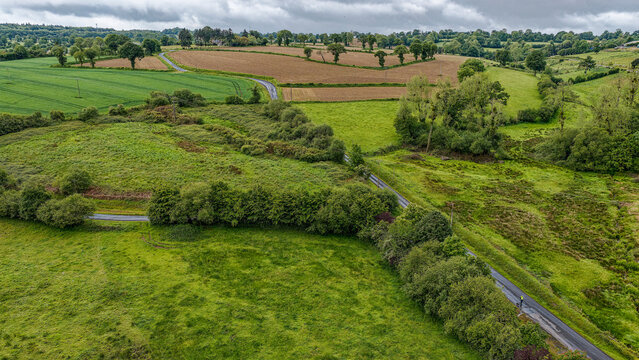 Rural country road winding through green fields in Normandy