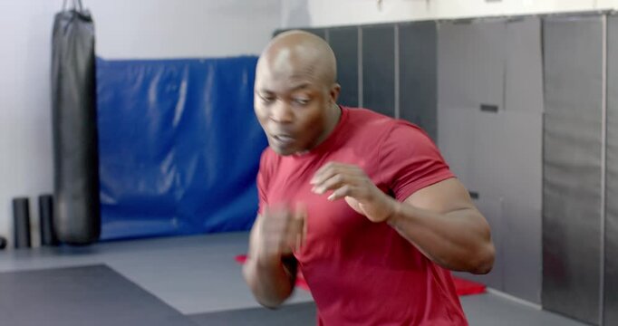 African American man starting shadow-boxing in gym, slipping punches and throwing combos for speed