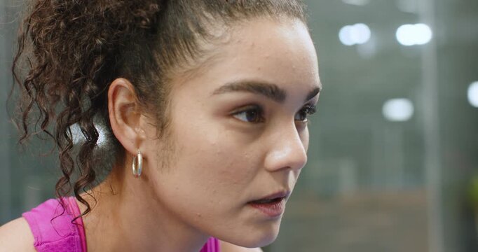 After finishing set, female athlete sitting on gym bench breathing, gathering focus for next rep