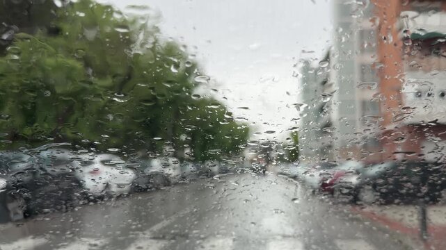 Raindrops on Car Windshield with Blurred City Street Background