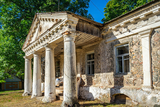 Ruined historic outbuilding facade of Zavishey estate with classic stone columns in Kukhtichi, Belarus.