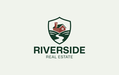 Obraz premium Real estate logo template featuring a house emblem with a winding river and valley landscape inside a shield for lakeside property investment and rural brokerage