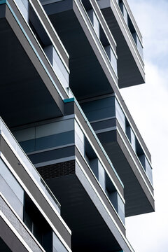 Gray balconies project from a facade with vertical shadows and lines, shaping an urban architecture building exterior of layered depth