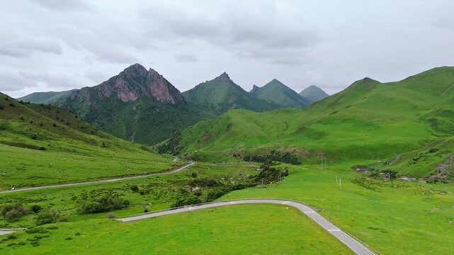 Aerial View of Winding Road Through Lush Green Grasslands and Mountains in Gannan, Gansu Province, China