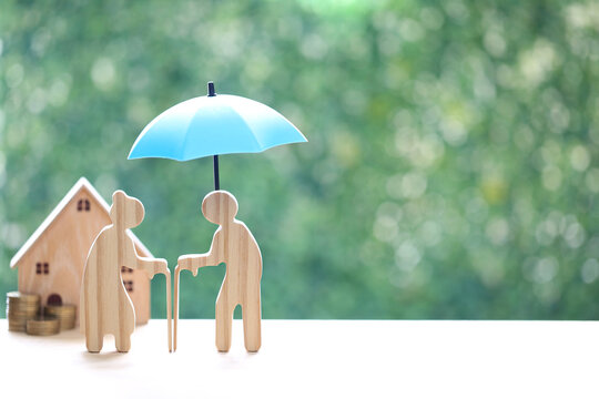 Couple wooden figures standing with a miniature house and coins, representing retirement home planning, property investment, real estate for seniors and financial security for old age