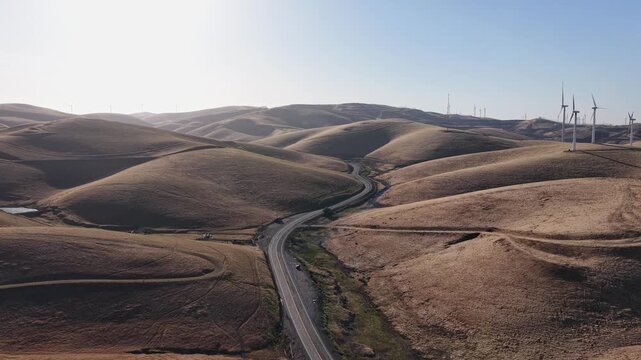 A drone view captures the Altamont Pass landscape, where wind turbines line the ridges and a curving road weaves through the hills, reflecting the region&rsquo;s blend of infrastructure and nature.