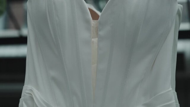 A close-up view of a white dress featuring intricate pleats and an elegant neckline. Ideal for fashion design inspiration or bridal catalogues.