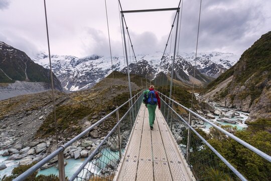 Hiker proceeds suspension bridge over River Hooker, Hooker Valley, Mount Cook National Park, Canterbury Region, New Zealand
