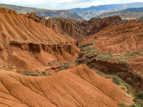 Hiker standing in badlands, gorge with eroded red sandstone rocks, Konorchek Canyon, Boom Gorge, aerial view, Kyrgyzstan