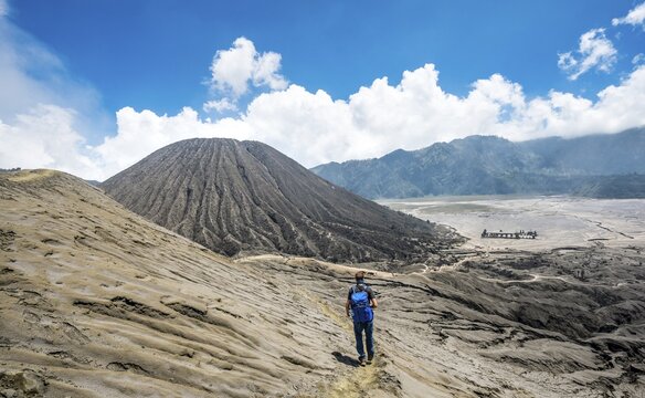 Young man on a narrow path at the crater rim of the volcano Gunung Bromo, behind Mt. Batok, National Park Bromo-Tengger-Semeru, Java, Indonesia