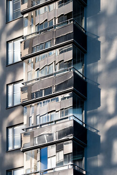 Deep shadow crosses a Stockholm apartment building facade, where balconies and windows give modern residential urban architecture layered depth