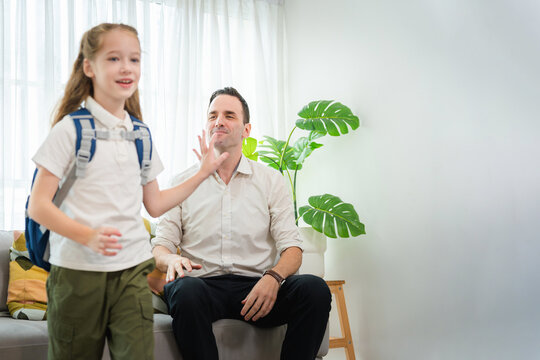 Happy father waving goodbye to daughter with school backpack at home, Father and little daughter preparing for school, Dad saying farewell to smiling school girl child before going to school