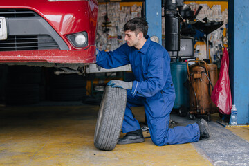 Fototapeta premium Auto mechanic worker changing car tire in auto workshop garage, Vehicle tyre maintenance service