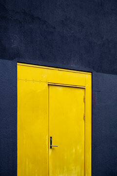 A yellow door punctuates a blue facade, where bold contrast makes urban architecture a minimal building exterior with clean detail