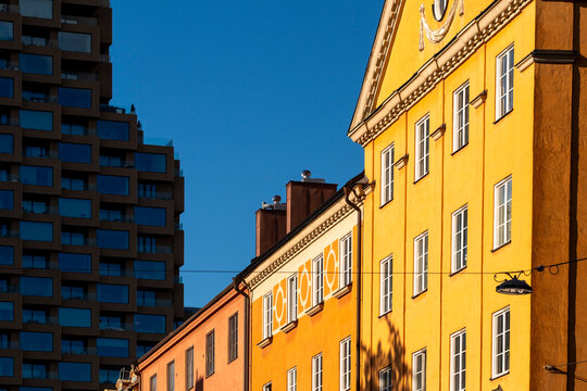 Sunlight warms a yellow facade beneath blue sky, where windows give urban architecture a bright building exterior with strong contrast