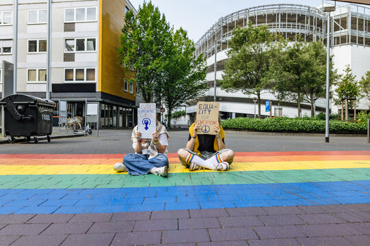 Demonstrator holding equality sign on rainbow street
