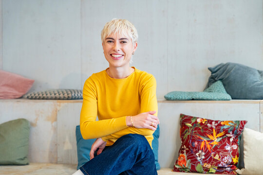 Smiling executive in yellow shirt sitting in a modern office