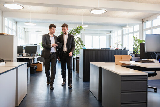 Business executives looking at a tablet while walking in the office