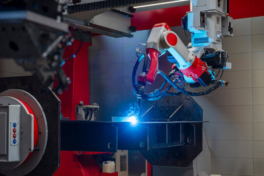 Automated industrial robotic arm welding metal parts in a factory