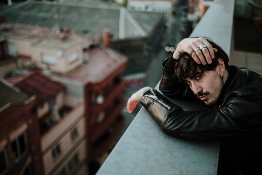 Fashion model leaning on urban balcony looking at camera