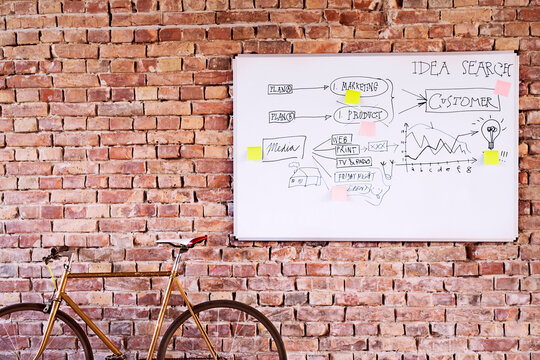 Bicycle and whiteboard with keywords at brick wall in office