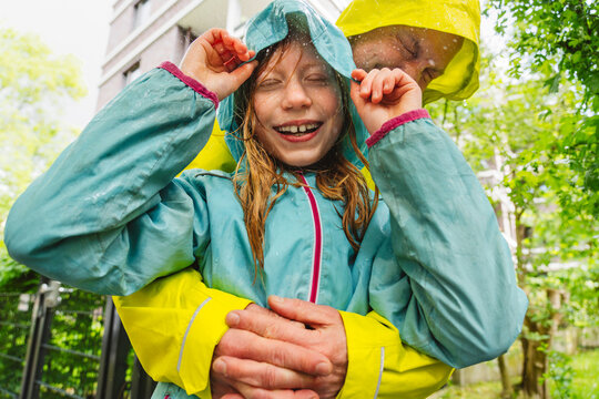Father and daughter wearing raincoats hugging outdoors in the rain